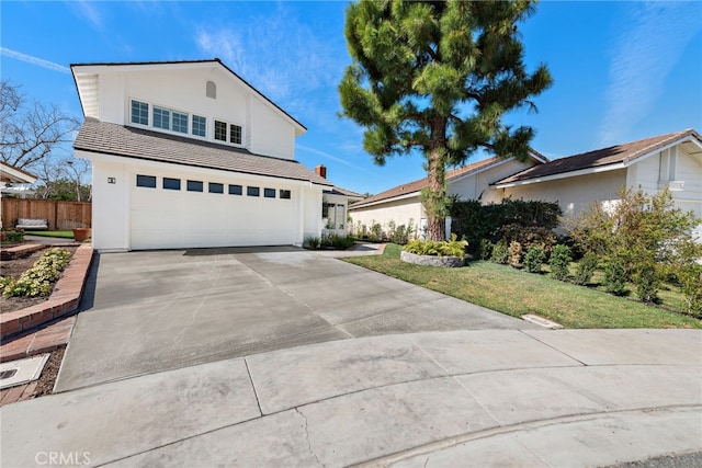 traditional home featuring concrete driveway, an attached garage, fence, and stucco siding