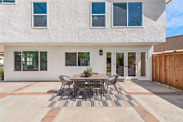 back of house featuring french doors, stucco siding, outdoor dining space, a patio area, and fence