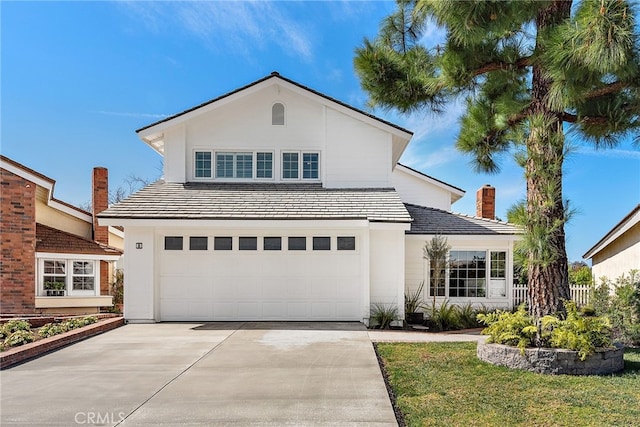 view of front of property featuring driveway, an attached garage, a chimney, and stucco siding