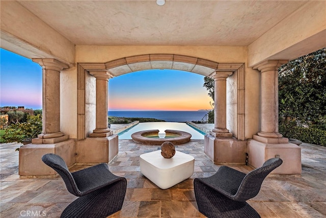 patio terrace at dusk featuring an outdoor pool and an in ground hot tub