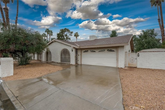 single story home featuring an attached garage, a shingled roof, driveway, a gate, and stucco siding