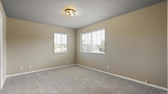 carpeted empty room featuring baseboards