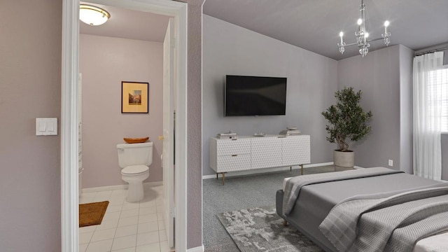 bedroom featuring baseboards, light tile patterned flooring, ensuite bathroom, and a notable chandelier