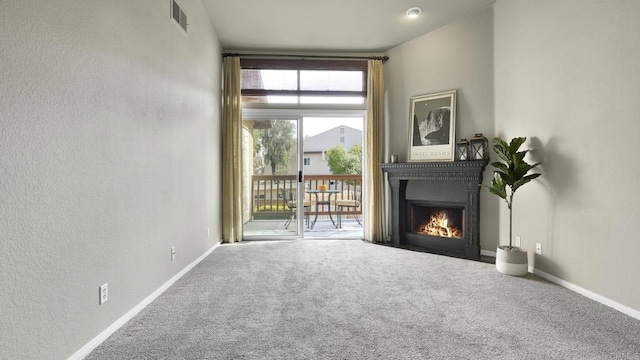 living area with carpet flooring, a fireplace with flush hearth, visible vents, and baseboards