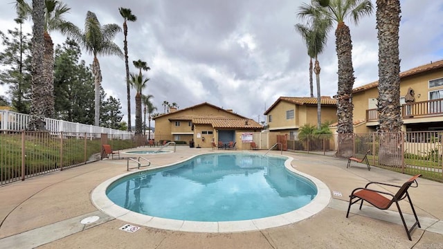 pool featuring a patio area, fence, and a hot tub