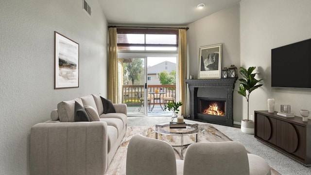 living room featuring carpet, a warm lit fireplace, and visible vents