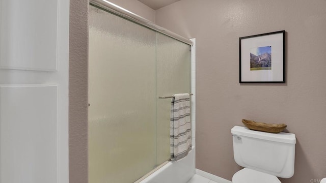 bathroom featuring toilet and bath / shower combo with glass door