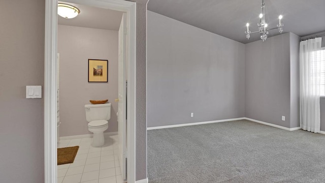 bathroom featuring tile patterned flooring, baseboards, toilet, and an inviting chandelier