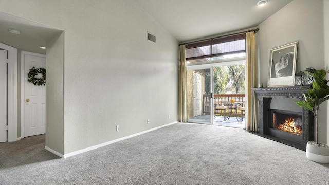 unfurnished living room with baseboards, visible vents, a fireplace with flush hearth, vaulted ceiling, and carpet flooring