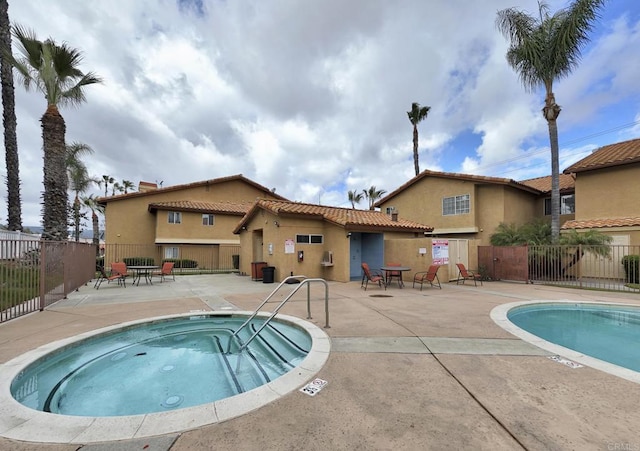 view of swimming pool featuring a patio area, fence, and a hot tub