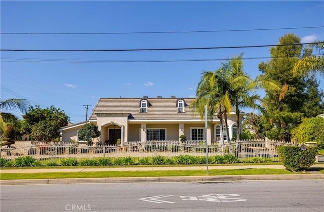 view of property featuring a fenced front yard, a tile roof, and stucco siding