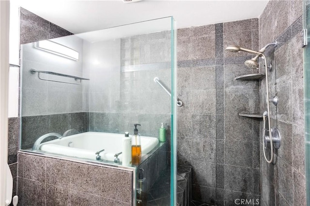 bathroom featuring a relaxing tiled tub and a tile shower