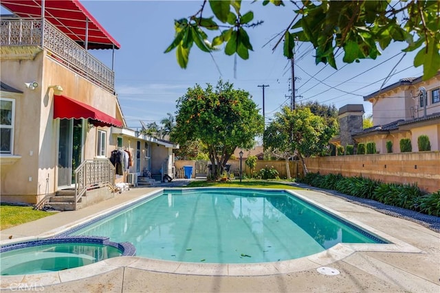 view of pool featuring a pool with connected hot tub and fence