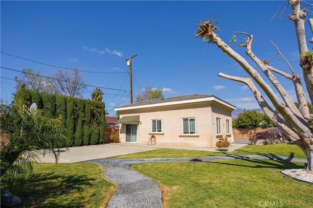 back of house with a yard, a patio, and stucco siding