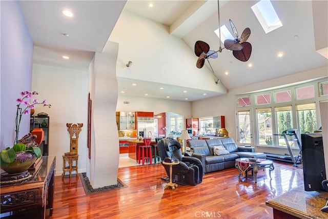 living room featuring a skylight, recessed lighting, visible vents, wood finished floors, and high vaulted ceiling