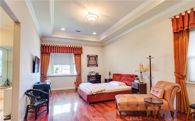 bedroom with a raised ceiling, visible vents, ornamental molding, a wood stove, and wood finished floors