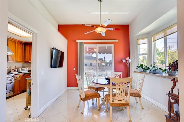 dining space featuring a toaster, baseboards, a ceiling fan, and light tile patterned flooring