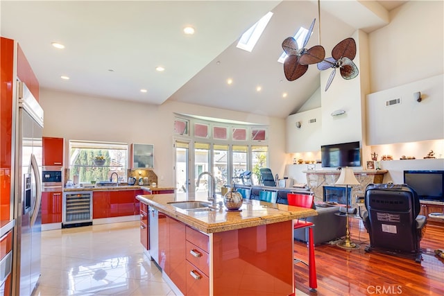 kitchen featuring beverage cooler, modern cabinets, a kitchen breakfast bar, high vaulted ceiling, and a sink