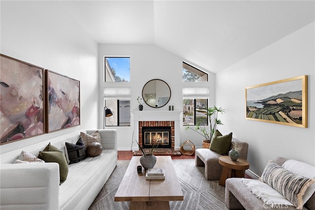 living area with high vaulted ceiling, a brick fireplace, baseboards, and wood finished floors