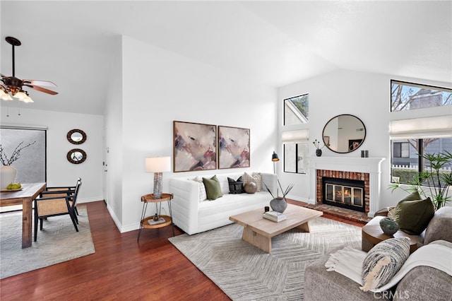 living room featuring high vaulted ceiling, dark wood finished floors, a brick fireplace, and plenty of natural light