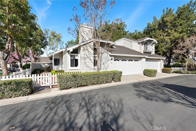 view of front of property with concrete driveway, a chimney, an attached garage, and fence