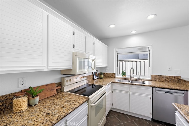 kitchen featuring white appliances, dark tile patterned flooring, white cabinetry, a sink, and recessed lighting