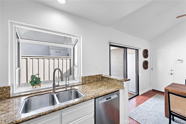 kitchen with light stone counters, a sink, white cabinets, vaulted ceiling, and stainless steel dishwasher