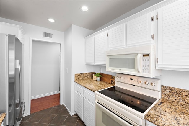 kitchen featuring recessed lighting, dark tile patterned flooring, white appliances, visible vents, and white cabinets