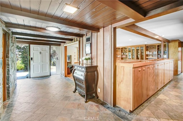 interior space with wood ceiling, beamed ceiling, and stone finish flooring