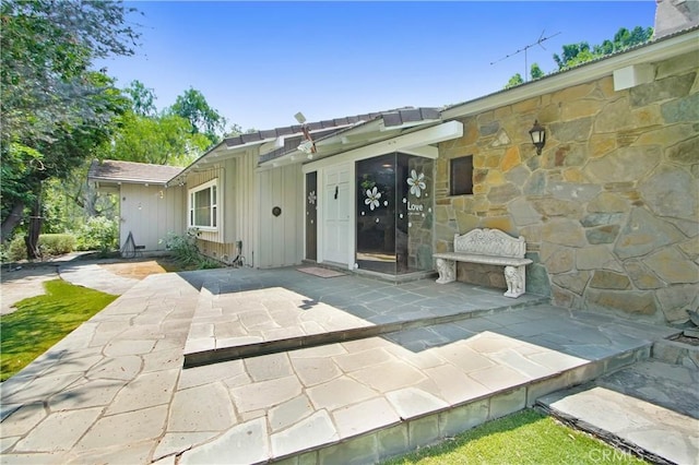 rear view of house featuring stone siding, a fireplace, and a patio