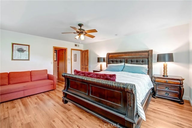 bedroom featuring a ceiling fan, visible vents, and wood finished floors