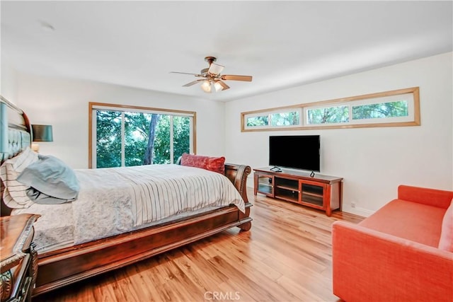 bedroom with ceiling fan, light wood-style flooring, and baseboards