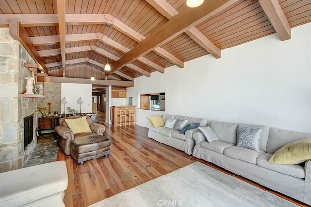 living room with wood ceiling, vaulted ceiling with beams, a stone fireplace, and wood finished floors