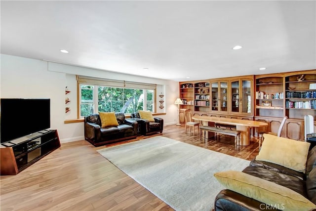 living area featuring baseboards, light wood-type flooring, and recessed lighting