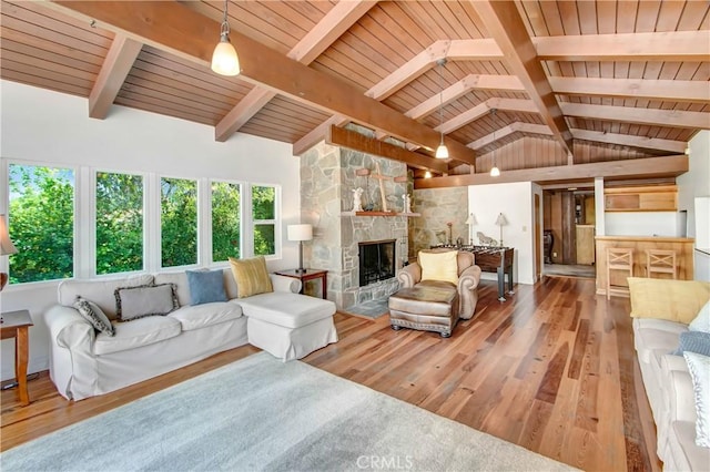 living area with wooden ceiling, a fireplace, vaulted ceiling with beams, and wood finished floors