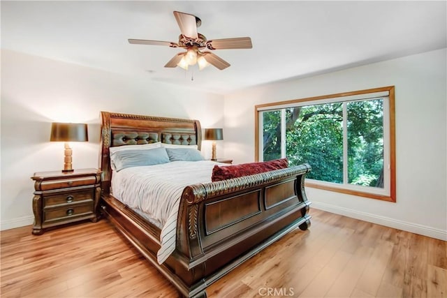 bedroom featuring a ceiling fan, light wood-style flooring, and baseboards