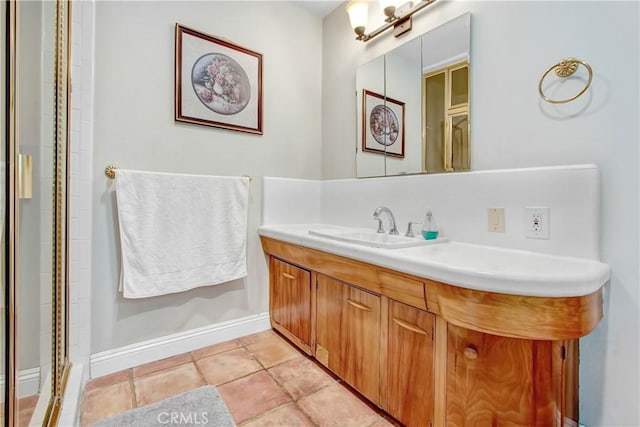 bathroom featuring tile patterned flooring, a shower with door, vanity, and baseboards