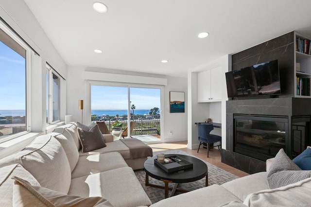 living room featuring light wood-style floors, recessed lighting, baseboards, and a premium fireplace