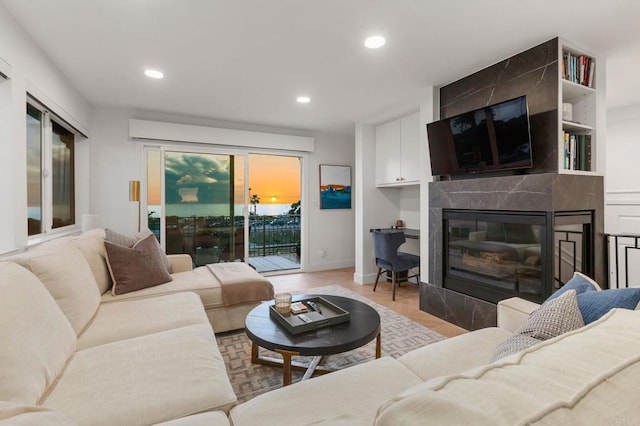 living room with baseboards, light wood-style flooring, a high end fireplace, and recessed lighting