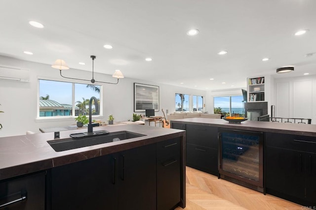 kitchen featuring a sink, a healthy amount of sunlight, beverage cooler, and dark cabinetry