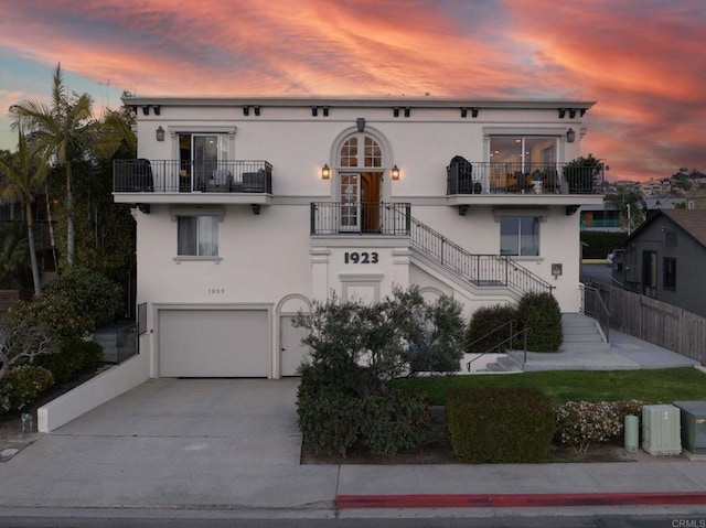 view of front of property with a garage, concrete driveway, stairway, and stucco siding