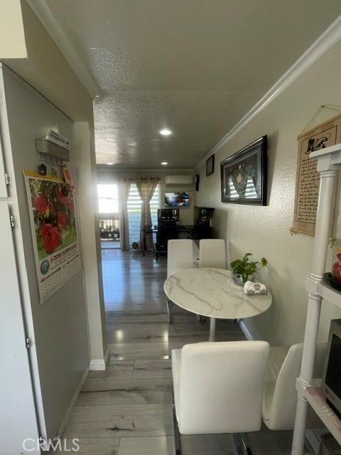 dining room with ornamental molding, light wood-style floors, a textured ceiling, and baseboards