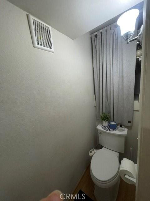 bathroom featuring toilet, wood finished floors, and visible vents