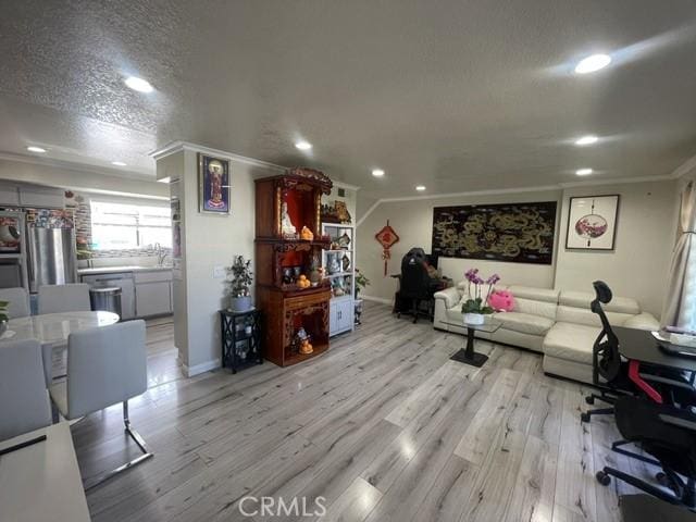 living room featuring crown molding, recessed lighting, light wood-style flooring, a textured ceiling, and baseboards