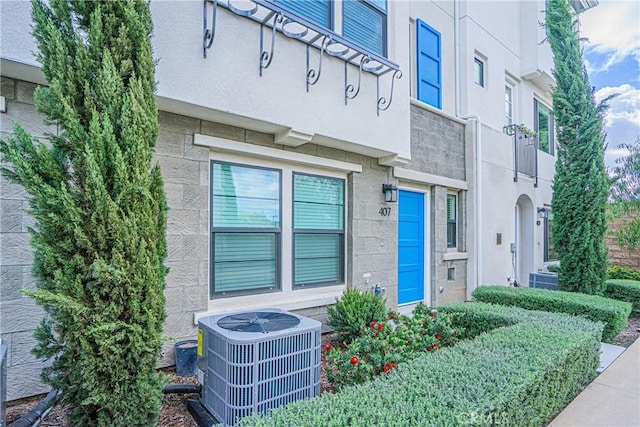 entrance to property featuring central AC and stucco siding