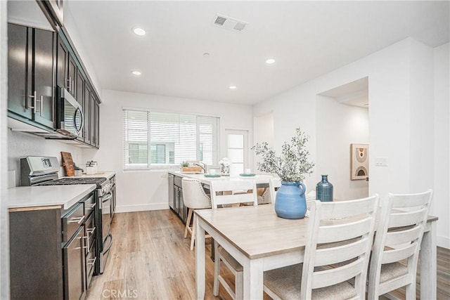 kitchen with visible vents, appliances with stainless steel finishes, light wood-style flooring, and a sink