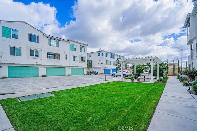 view of property's community featuring a yard, an attached garage, and a pergola