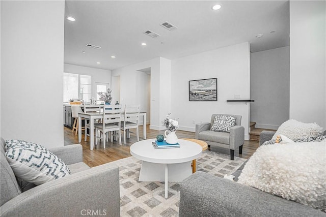 living area with baseboards, wood finished floors, visible vents, and recessed lighting