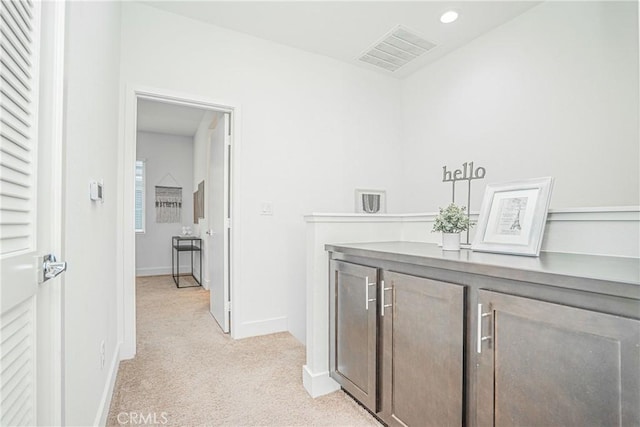 hallway featuring recessed lighting, visible vents, light carpet, and baseboards