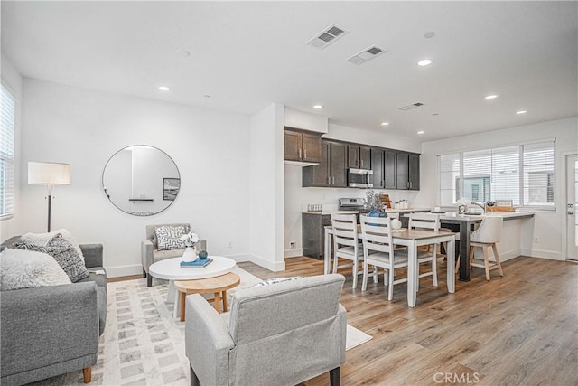 living area featuring light wood-type flooring, baseboards, visible vents, and recessed lighting